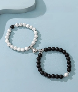 Close-up of magnetic heart clasp connecting black and white marble bead bracelets