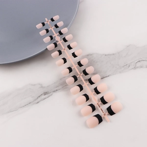 Detail of 24pcs classic French press-on nails with nude base and black tips on tray