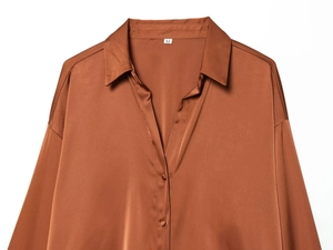 Detail of satin brown blouse showing lapel collar, smooth silk texture, and buttons