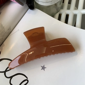 Detailed top view of a large glossy brown hair claw clip showing a thick minimalist resin design
