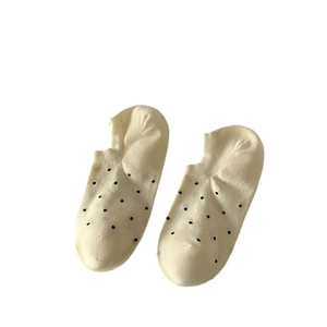 Pair of light yellow cotton boat socks with black polka dot patterns on a white background