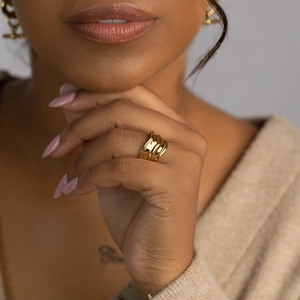 Close-up of a minimalist golden wave ring with hammered texture on a model finger
