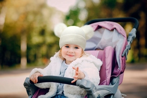 Close-up of baby wearing cream knit beanie with double pom-poms in an outdoor setting
