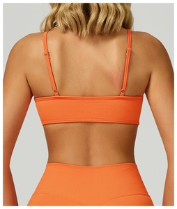 Makro-Detail des nahtlosen gerippten orangen Sport-BHs mit schmalen Trägern und Strickstoff
