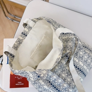 Detail view of cotton canvas tote bag with blue lace floral pattern and interior pocket