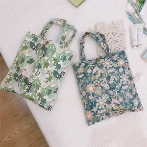 Détail de sacs en toile fleuris avec boutons-pression en métal et motifs botaniques variés