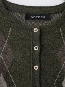 Détail du cardigan en maille à losanges vert foncé avec boutons brillants et col côtelé