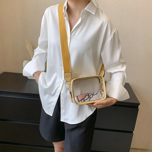 Detail view of transparent PVC crossbody bag with yellow strap and interior silk scarf detail