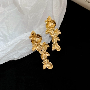 Makroaufnahme langer goldener Blumenohrringe mit realistischer Orchideen-Textur