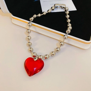 Detailed view of a silver beaded chain with a vibrant red resin heart pendant