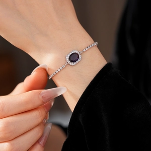 Adjustable silver bracelet with oval purple gemstone and cubic zirconia halo on wrist