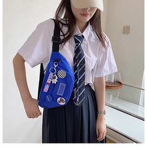 Close-up of blue canvas crossbody bag with astronaut pendant and fashion badges details