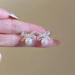 Elegant silver bow earrings featuring shimmering crystals and a dangling white pearl charm