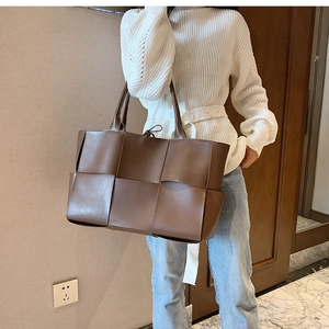 Brown woven leather tote bag carried by a model to show its large size and stylish look