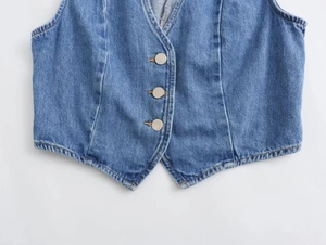 Vista macro dettagliata dei tre bottoni metallici e trama denim su un gilet blu