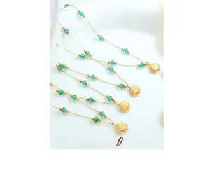 Detail of 18K gold plated necklaces with emerald green crystal beads and shell pendants