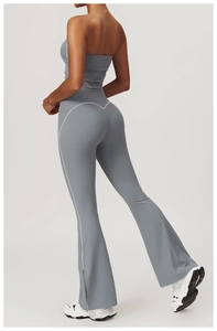 Detail of high-waist flared yoga pants with white stitching and side slit hem