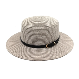 Detail of flat top straw boater hat with black faux leather band and gold buckle