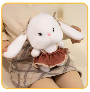 Close-up of plush white rabbit doll wearing a brown crochet dress and plaid bow detail