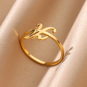 Macro detail of adjustable golden letter K ring on champagne satin fabric background