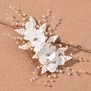 Detail of bridal hair comb with white fabric flowers and handcrafted pearl beadwork