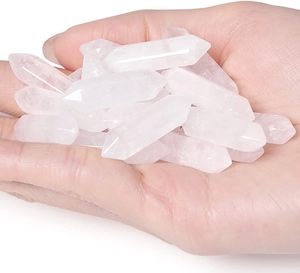 Macro view of several polished double terminated clear quartz crystal pillars on a hand