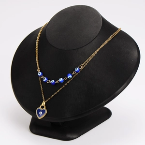 Double layer gold evil eye necklace with blue heart pendant on black jewelry display stand