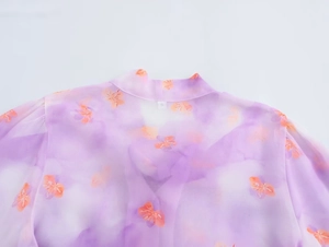 Detail view of purple floral chiffon blouse neckline with an S size label and ruffles