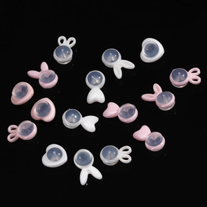 Macro detail of rabbit and heart-shaped pink ceramic earring backings on black base