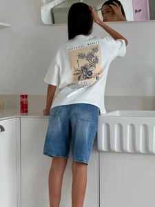 Πίσω όψη λευκού βαμβακερού T-shirt με βοτανικό τύπωμα και μπλε τζιν σορτς σε κουζίνα
