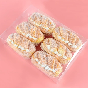 Detailed view of six artificial cream bread props with sugar powder in a plastic box