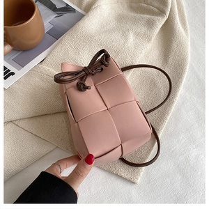 Detailed view of pink woven leather bucket bag with dark brown drawstring and strap
