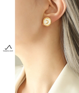 Close-up of gold stainless steel shell moon earrings worn by a female model