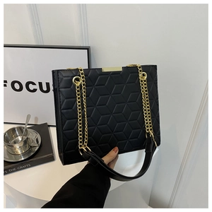 Detailed view of black geometric quilted handbag with gold chain strap in minimalist room