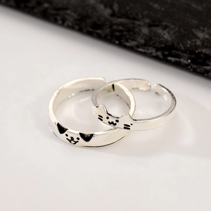 Detail of silver-colored gothic cat rings with black cat face patterns and open design
