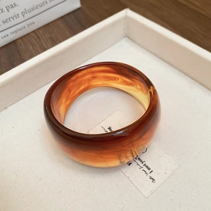 Detailed close-up of a wide amber resin bangle with natural fluid swirl textures