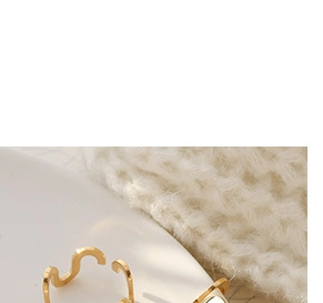 Détail de boucles d'oreilles dorées ondulées sur un fond de tissu en maille blanc