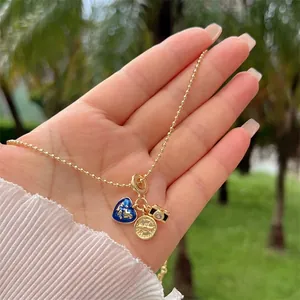 Λεπτομέρεια από επιχρυσωμένο κολιέ 18K με μπλε καρδιά παγκόσμιο χάρτη και κάμερα