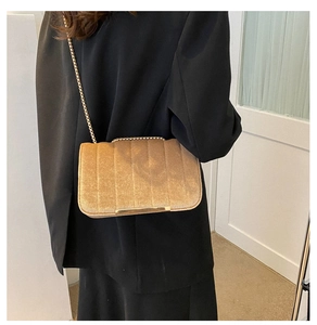 Detail view of champagne velvet small bag featuring vertical quilted texture and gold chain