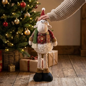 Detail of Christmas sheep plush with red plaid jacket and long legs by festive tree