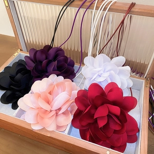 Macro detail of 3D fabric flower necklaces in five colors within a wooden jewelry box