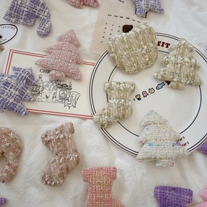 Flat lay of handmade tweed Christmas ornaments with sequins in pastel colors on white cloth
