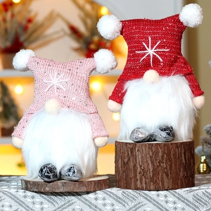 Close-up of pink and red Christmas gnomes with knit hats and warm LED lights