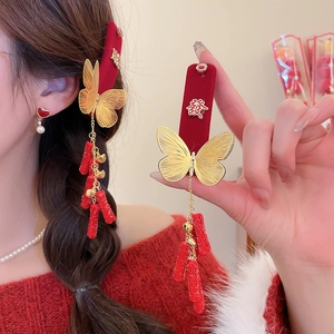 Detail of red velvet butterfly hair clip with gold metal charms and festive tassels