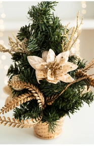 Close-up of mini Christmas tree with gold ornaments and beige glitter flowers
