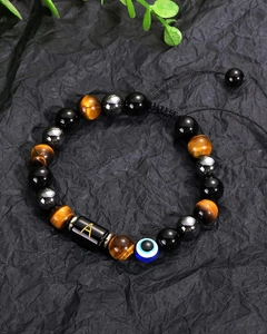 Tiger eye stone bracelet with evil eye bead and golden letter A charm on black fabric