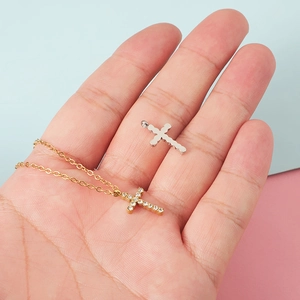 Cross pendant necklaces in gold with crystals and silver steel finish held in hand