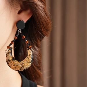Detail of vintage moon drop earrings with gold foil and resin worn by model