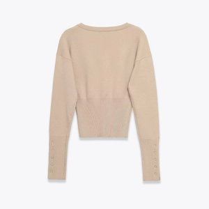 Rückansicht des beigen Strickpullovers mit Rippbündchen und metallischen Zierknöpfen