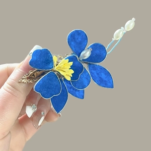 Dettaglio ravvicinato di un fermaglio per capelli a fiore blu con accenti di perle